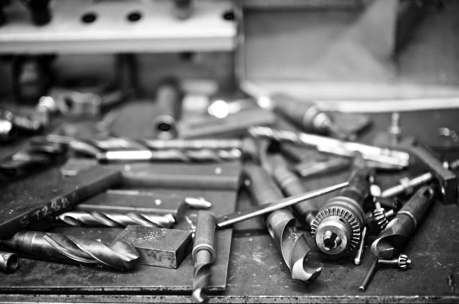 Close-up of assorted drill bits and workshop tools scattered across a work table