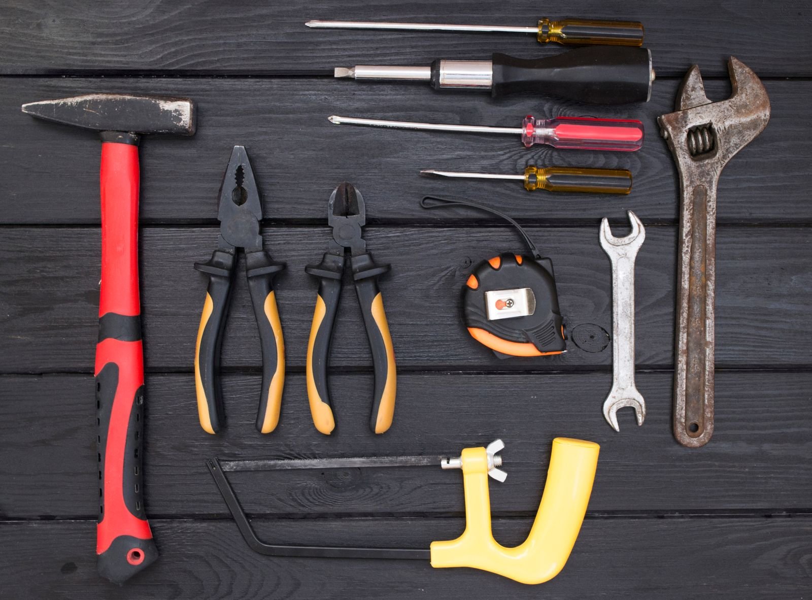 Basic home improvement hand tools laid out neatly, including a hammer, pliers, screwdrivers and a wrench