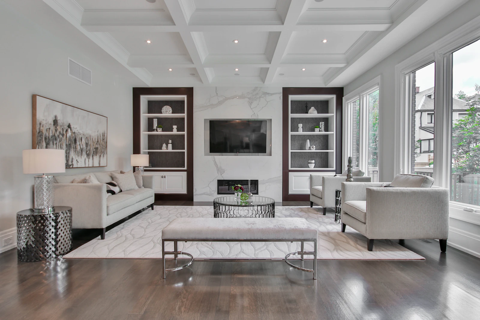 Elegant living room with a marble fireplace wall, built-in shelving and neutral upholstered seating