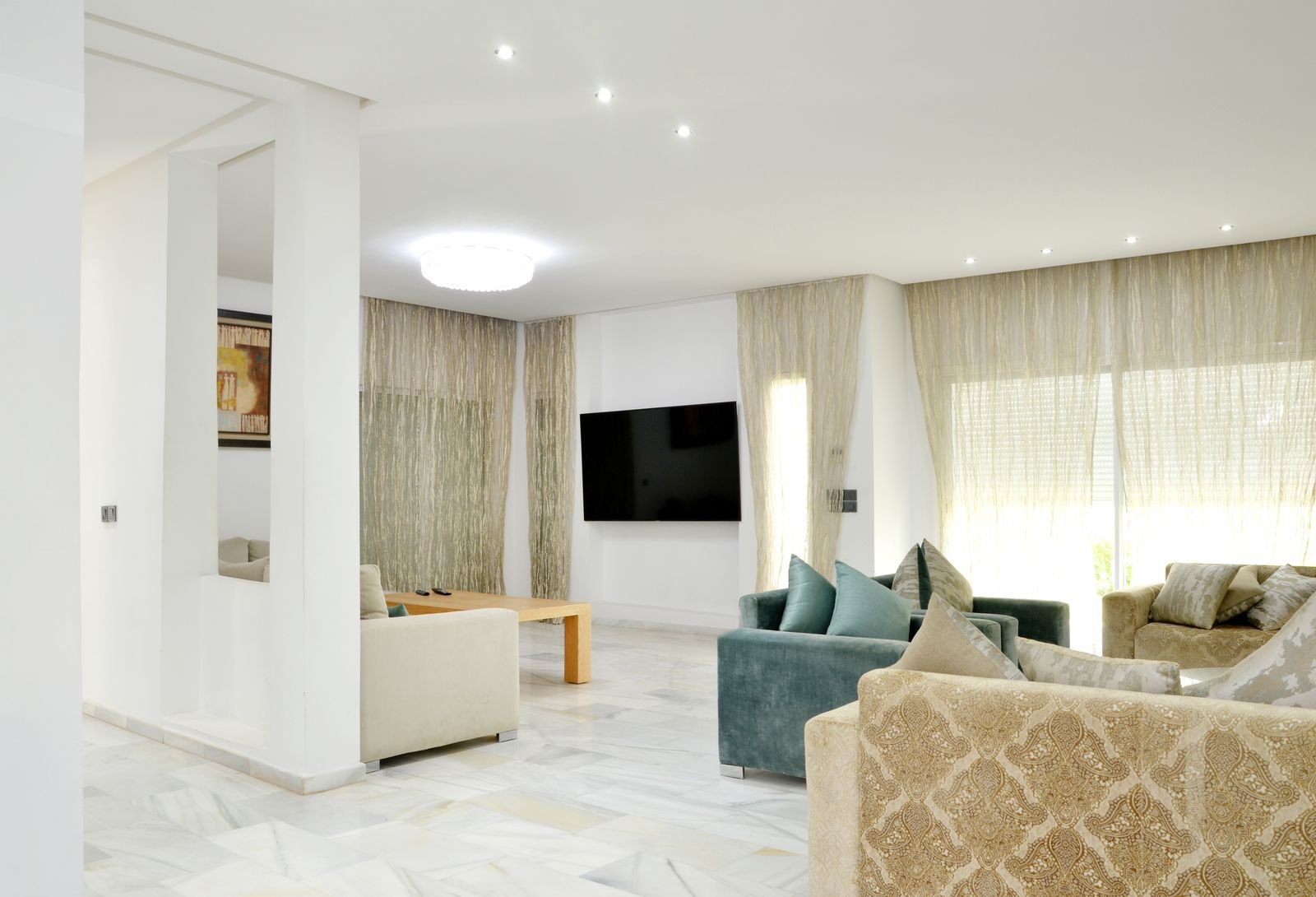 Bright luxury living room with marble flooring, sheer floor-to-ceiling curtains and upholstered seating