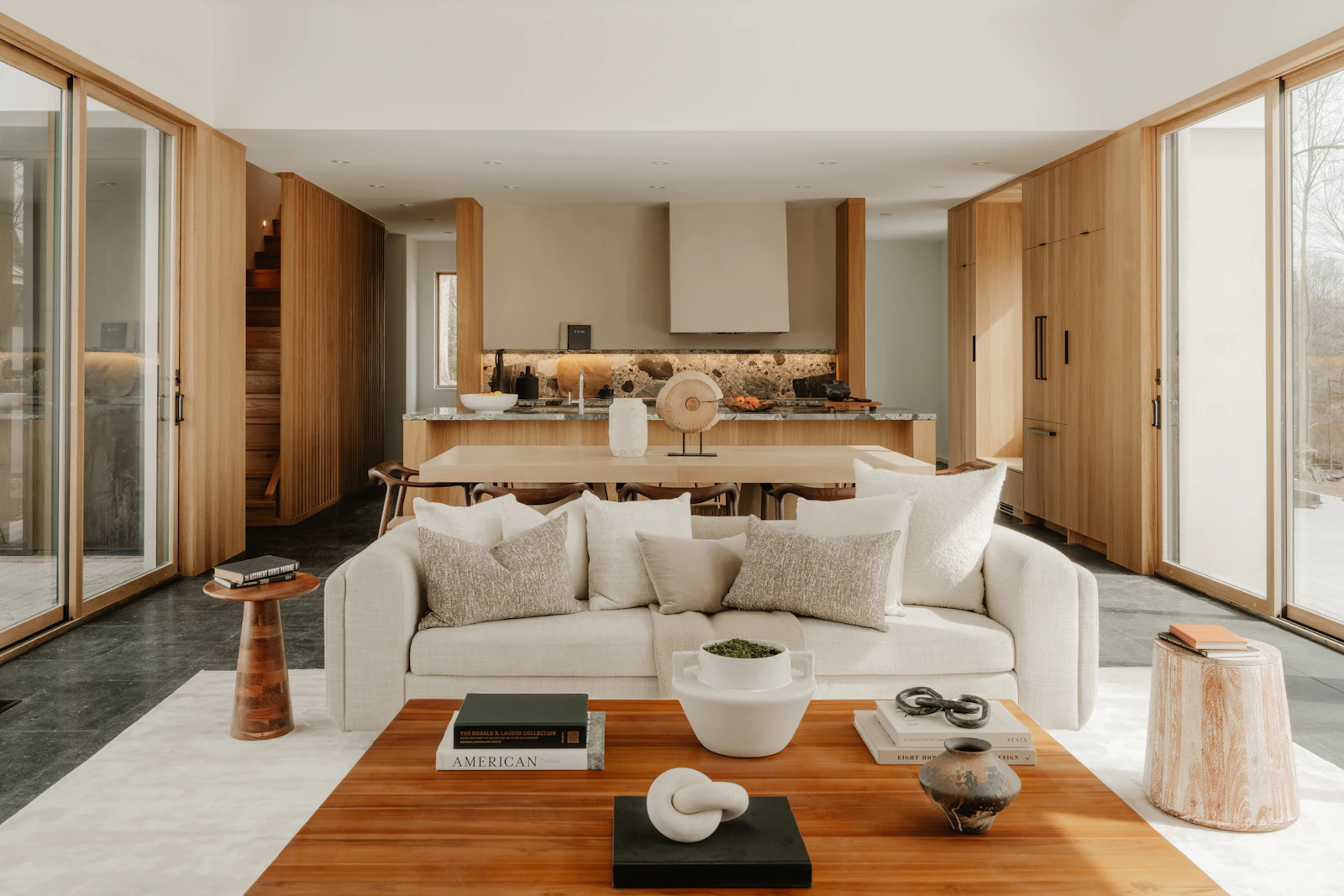 Modern open-plan living space with clean-lined furniture, natural wood tones and a connected kitchen