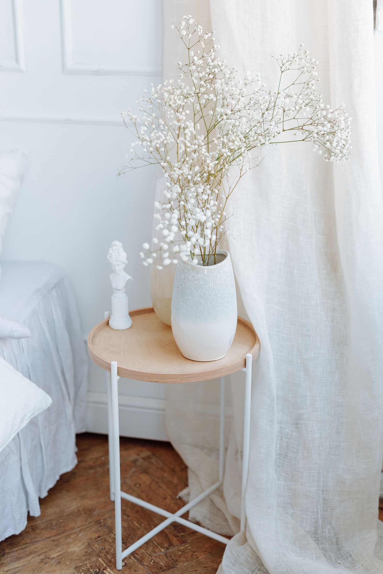Round wood tray table styled with a ceramic vase of dried flowers and a small sculptural bust