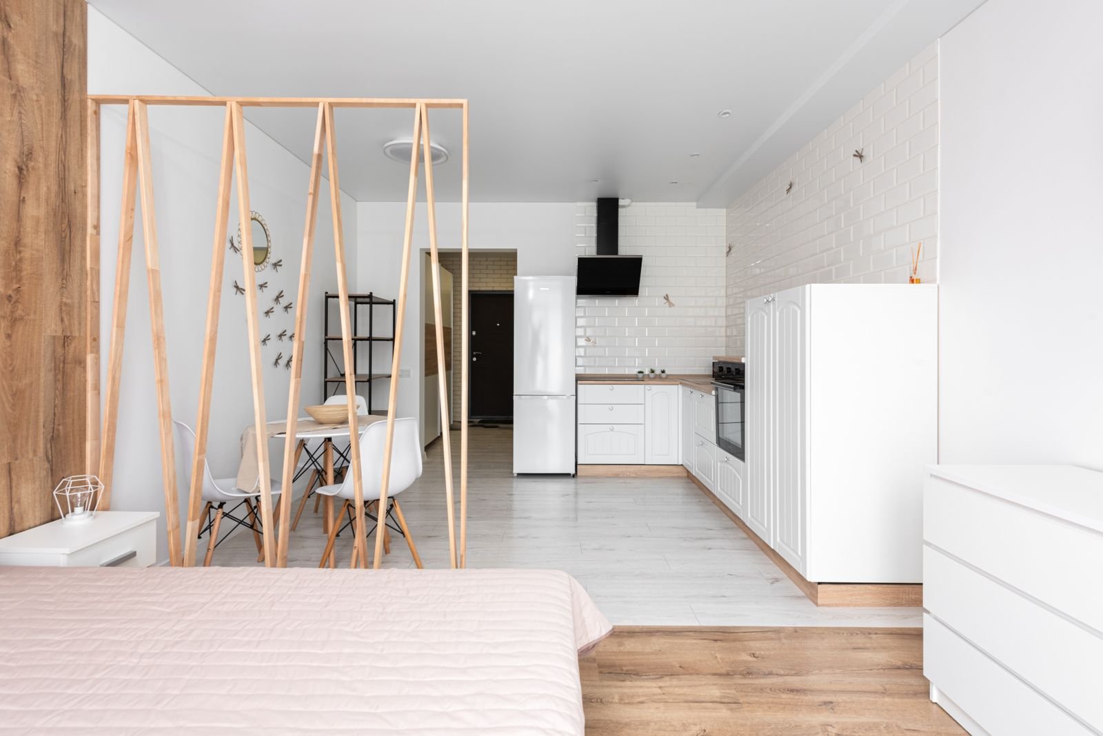 Small studio apartment with a wood room divider separating the bed from a compact dining and kitchen zone