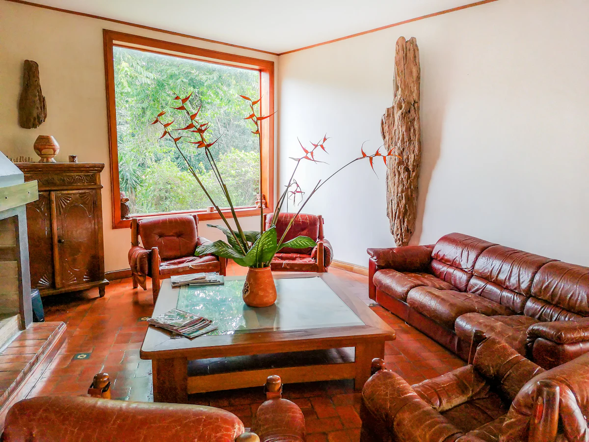 Vintage-style living room with worn burgundy leather sofas, a hand-carved wood cabinet and terracotta tile flooring