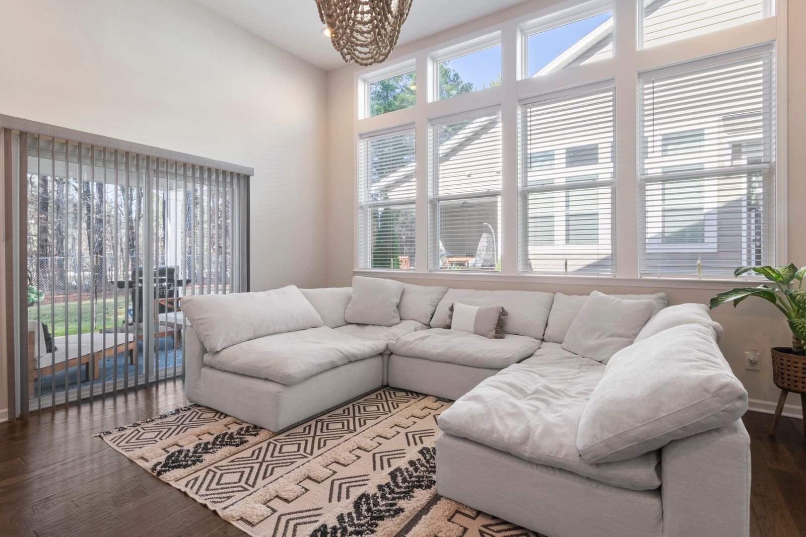 Refined living room with a plush white sectional sofa, patterned layered rug and tall bright windows